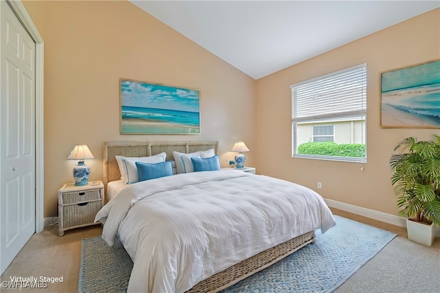 bedroom featuring a closet, light colored carpet, and lofted ceiling