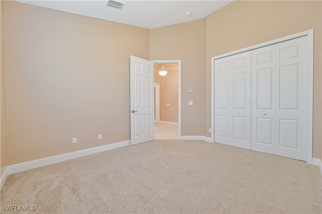 unfurnished bedroom with light carpet and a closet