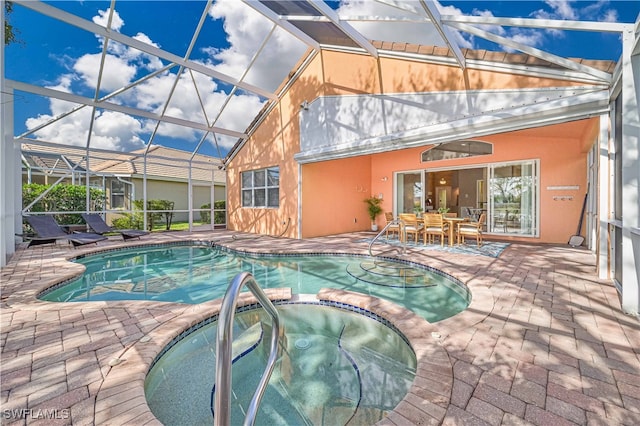 view of pool with glass enclosure, a patio area, and an in ground hot tub