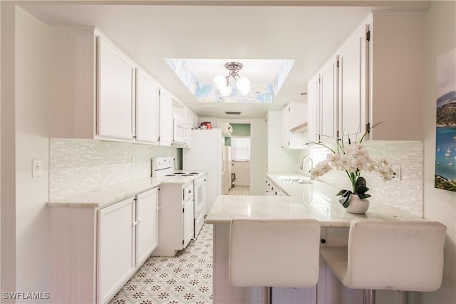 kitchen with white cabinets, stove, kitchen peninsula, and a kitchen breakfast bar