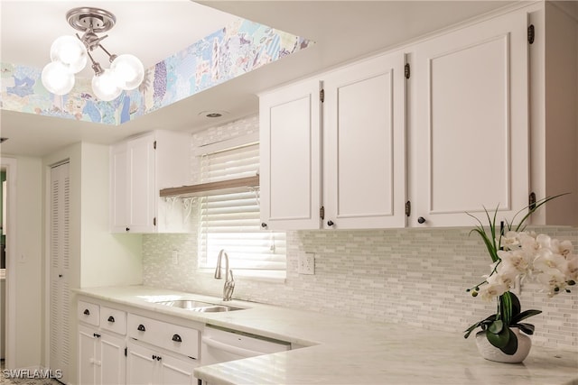 kitchen with white cabinets, decorative backsplash, sink, and white dishwasher