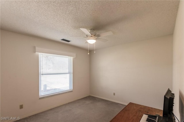 carpeted empty room featuring ceiling fan and a textured ceiling