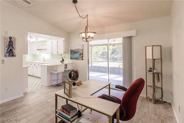 office space with a notable chandelier, light wood-type flooring, lofted ceiling, and sink