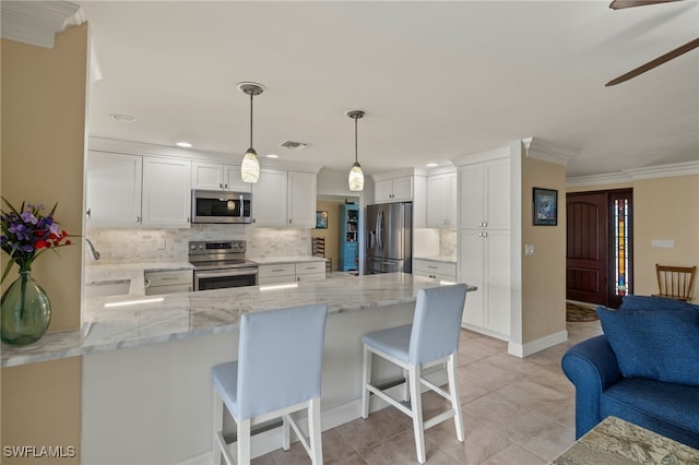 kitchen featuring crown molding, kitchen peninsula, hanging light fixtures, white cabinetry, and stainless steel appliances