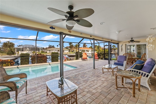 exterior space featuring glass enclosure, ceiling fan, a water view, and a patio