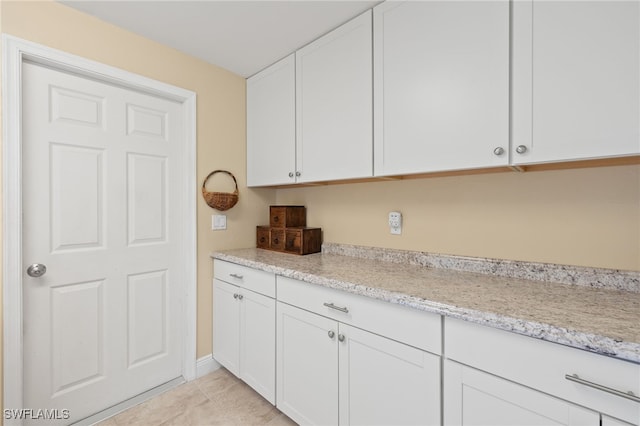 kitchen with white cabinets, light tile patterned flooring, and light stone countertops