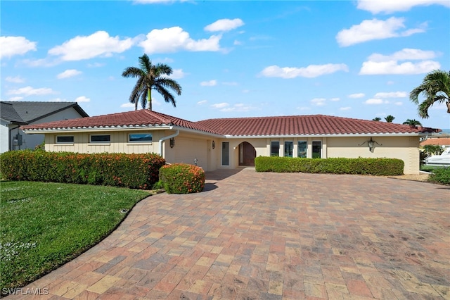 mediterranean / spanish house featuring a front yard and a garage