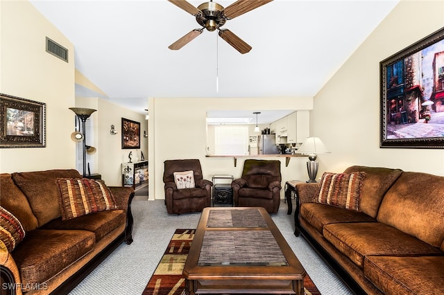 carpeted living room with ceiling fan and vaulted ceiling