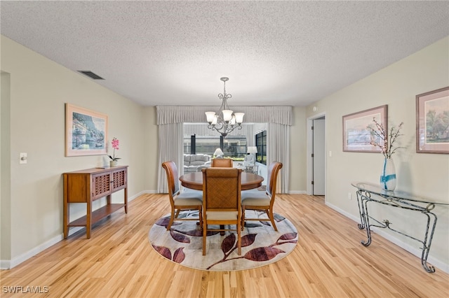 dining space featuring light hardwood / wood-style floors, a chandelier, and a textured ceiling