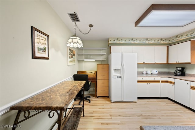 kitchen with decorative light fixtures, white cabinets, white refrigerator with ice dispenser, and light wood-type flooring