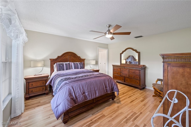 bedroom with a textured ceiling, ceiling fan, and light hardwood / wood-style floors