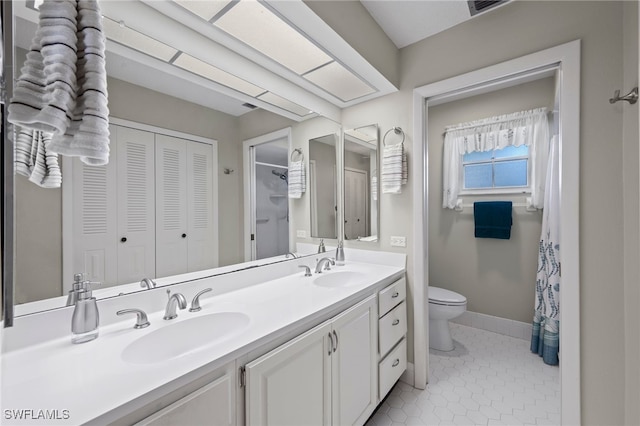 bathroom with toilet, vanity, and tile patterned floors