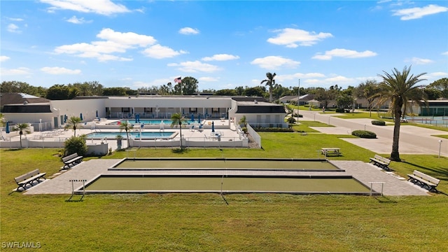 rear view of house with a community pool and a lawn