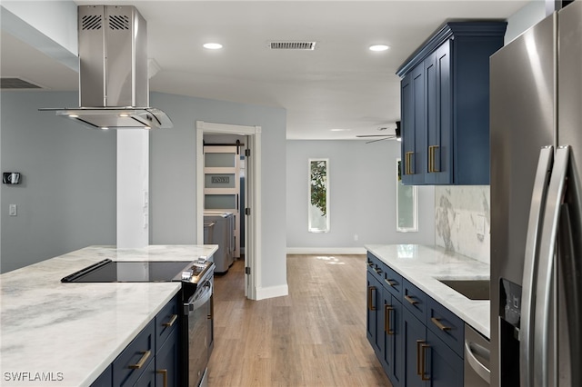 kitchen with washer and clothes dryer, ventilation hood, light stone countertops, appliances with stainless steel finishes, and light hardwood / wood-style floors