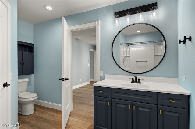 bathroom with ceiling fan, walk in shower, wood-type flooring, toilet, and vanity