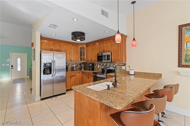 kitchen with kitchen peninsula, decorative backsplash, light stone counters, stainless steel appliances, and pendant lighting