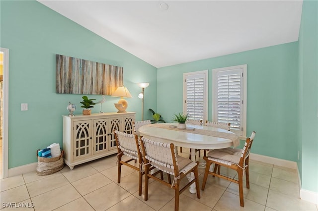 dining space with light tile patterned floors and vaulted ceiling