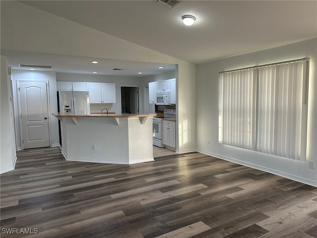 kitchen featuring white cabinets, white appliances, dark hardwood / wood-style floors, and vaulted ceiling