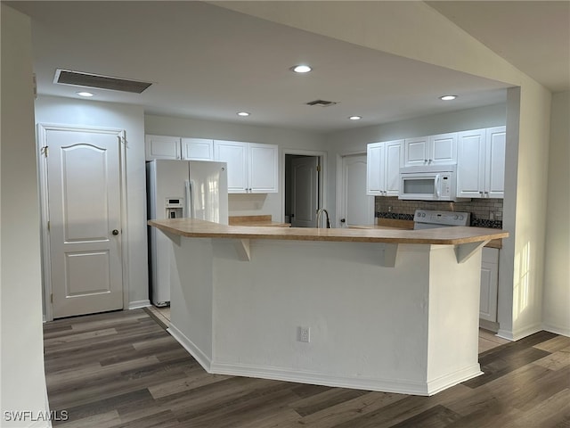 kitchen featuring a center island, a kitchen bar, white appliances, white cabinets, and dark hardwood / wood-style flooring