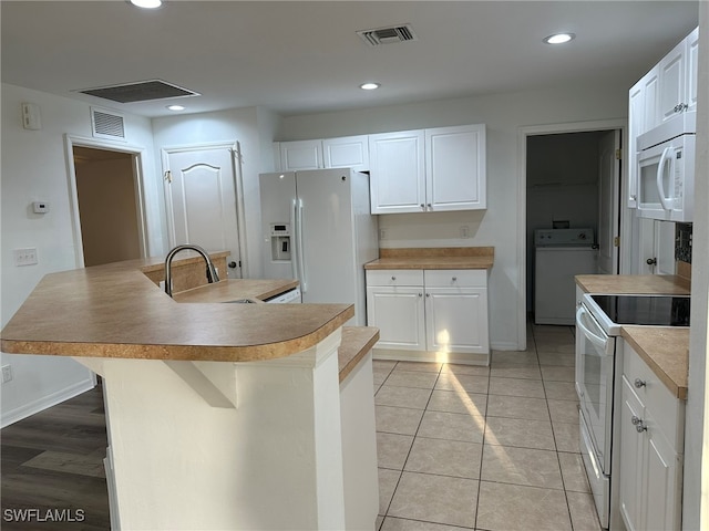 kitchen with white appliances, white cabinets, sink, an island with sink, and washer / dryer