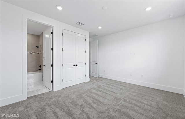 unfurnished bedroom featuring ensuite bathroom and light colored carpet