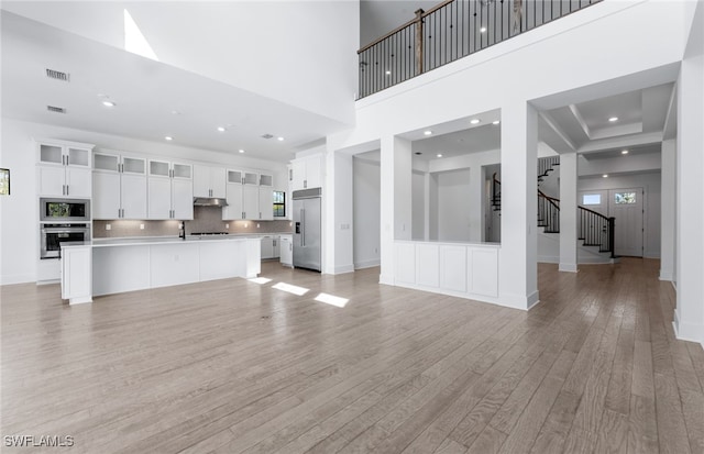 unfurnished living room with light hardwood / wood-style flooring and a towering ceiling