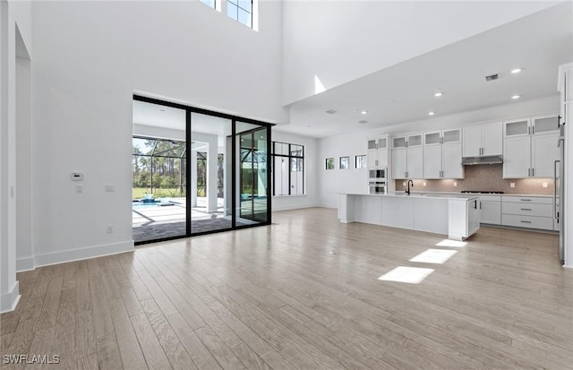 14111 Calaveras Ct, Estero, FL 33928 - unfurnished living room featuring plenty of natural light, light wood-type flooring, baseboards, a high ceiling, and recessed lighting
