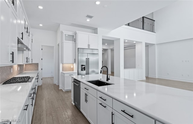 kitchen featuring white cabinets, sink, appliances with stainless steel finishes, light hardwood / wood-style floors, and light stone counters