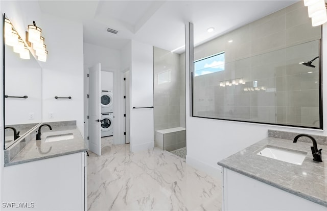 bathroom with a tile shower, stacked washer and dryer, and vanity