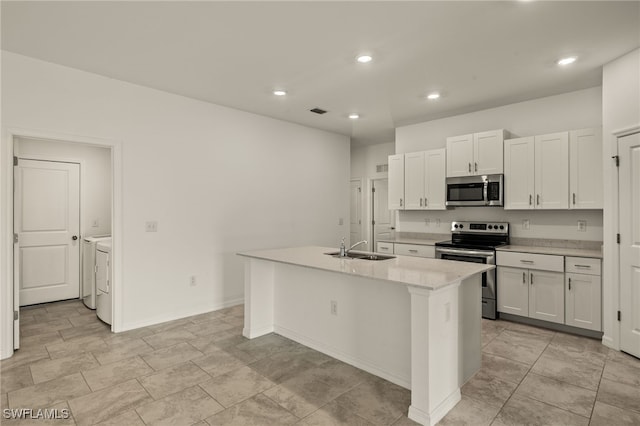 kitchen featuring appliances with stainless steel finishes, sink, washer and dryer, a center island with sink, and white cabinets