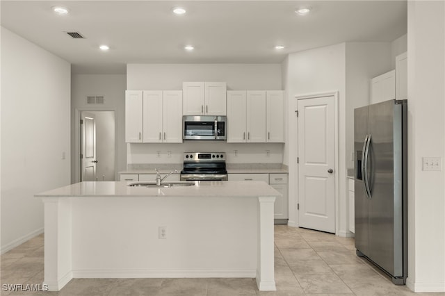 kitchen with a center island with sink, white cabinets, sink, appliances with stainless steel finishes, and light tile patterned flooring