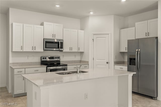 kitchen with light stone countertops, sink, an island with sink, white cabinets, and appliances with stainless steel finishes