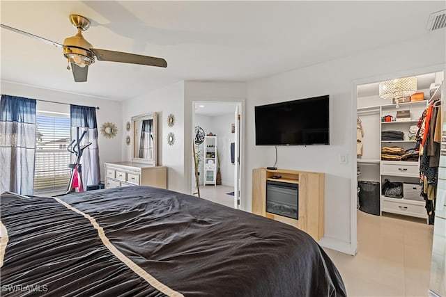 tiled bedroom with ceiling fan, a closet, and a spacious closet