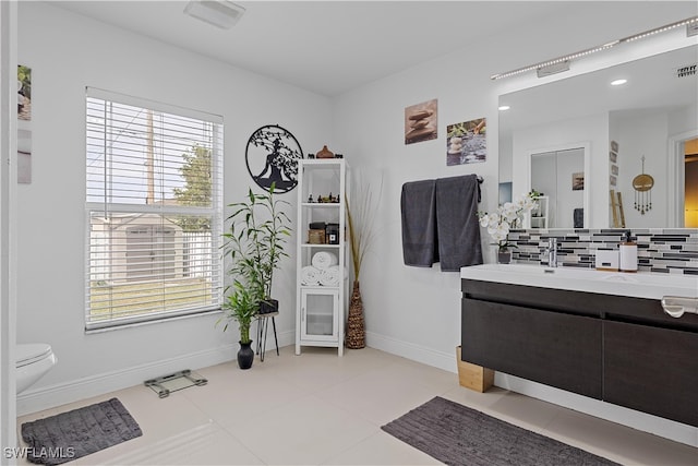 bathroom with tile patterned flooring, decorative backsplash, a healthy amount of sunlight, and vanity