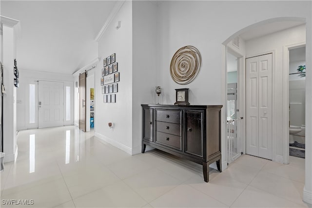 hallway featuring light tile patterned floors, crown molding, and vaulted ceiling