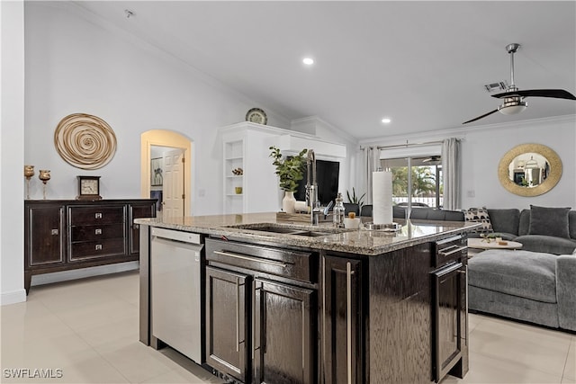 kitchen featuring dark brown cabinetry, crown molding, a center island with sink, and sink