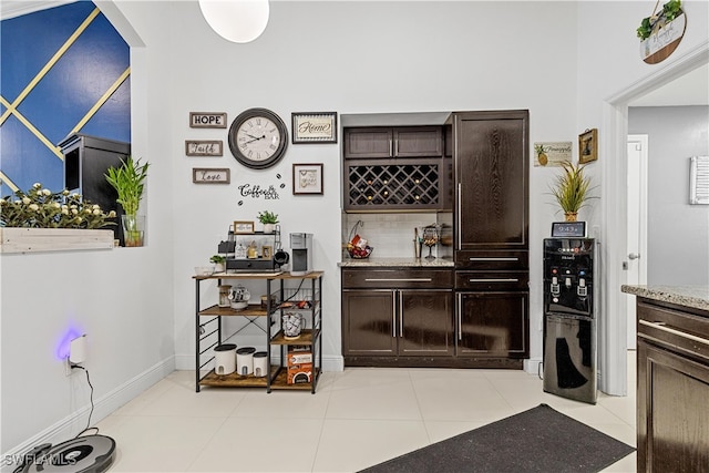 bar with light stone countertops, dark brown cabinets, and light tile patterned floors