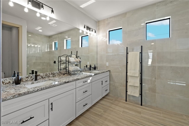 bathroom with vanity, tile walls, and tiled shower