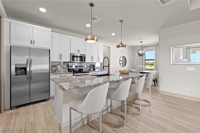 kitchen featuring sink, pendant lighting, a center island with sink, white cabinets, and appliances with stainless steel finishes