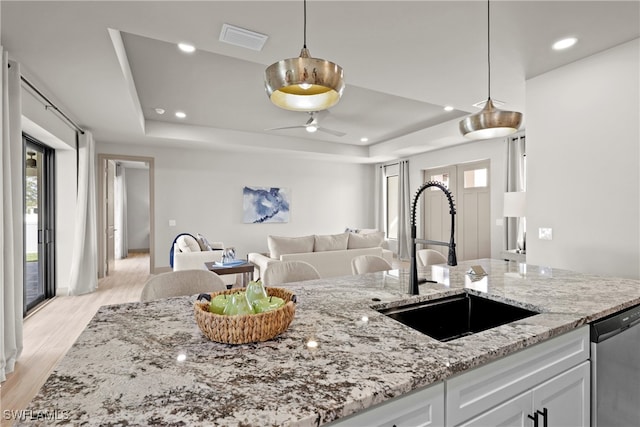 kitchen with dishwasher, white cabinets, sink, light stone countertops, and light hardwood / wood-style floors