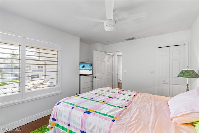 bedroom with a closet, visible vents, a ceiling fan, wood finished floors, and baseboards