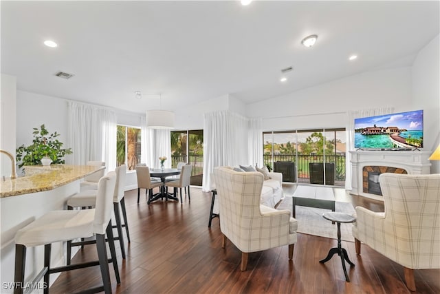 living area featuring visible vents, dark wood finished floors, vaulted ceiling, a fireplace, and recessed lighting