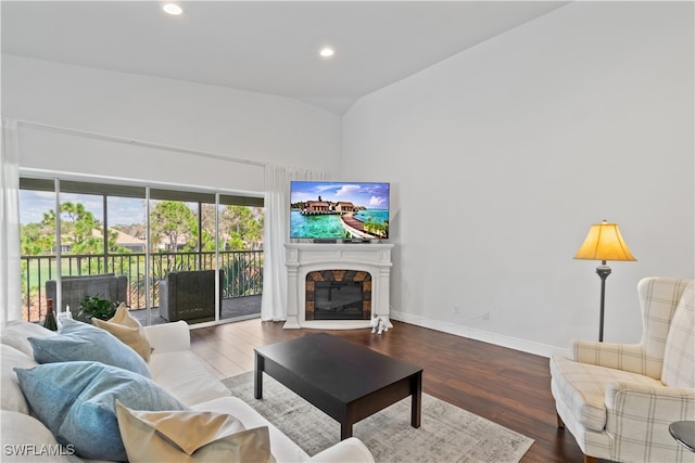 living area with baseboards, wood finished floors, vaulted ceiling, a fireplace, and recessed lighting