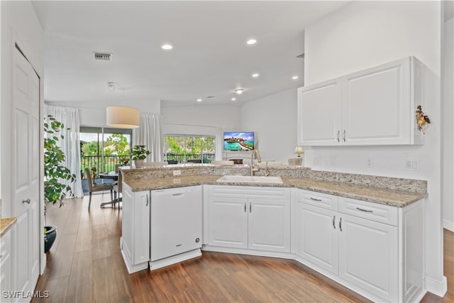 kitchen featuring a peninsula, wood finished floors, a sink, white cabinets, and dishwasher