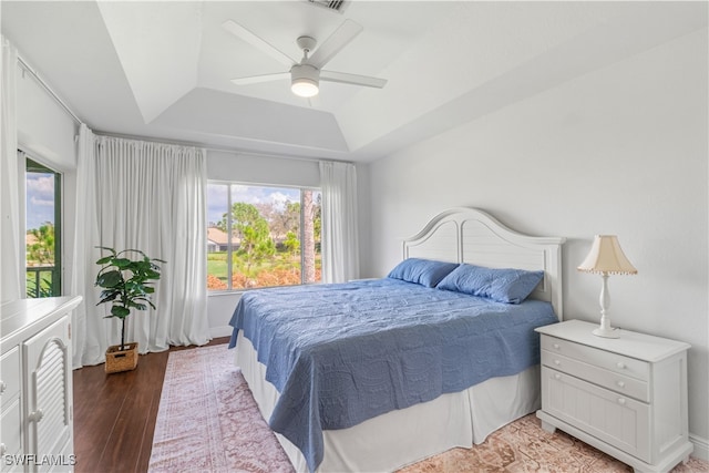 bedroom with visible vents, wood finished floors, a raised ceiling, and a ceiling fan