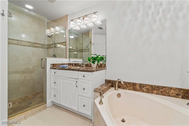 bathroom with a stall shower, vanity, and a bath