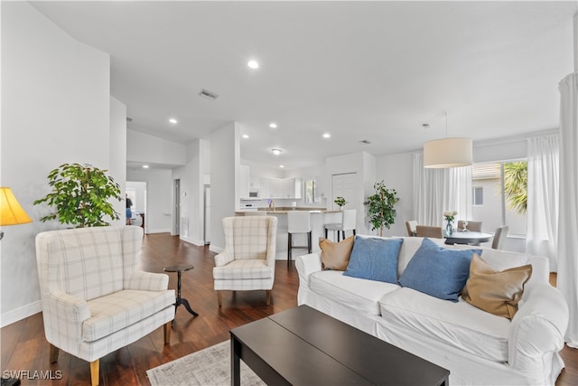 living area with dark wood-style floors, recessed lighting, lofted ceiling, visible vents, and baseboards