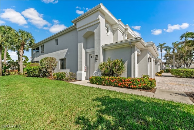 view of side of home featuring a yard, decorative driveway, and stucco siding