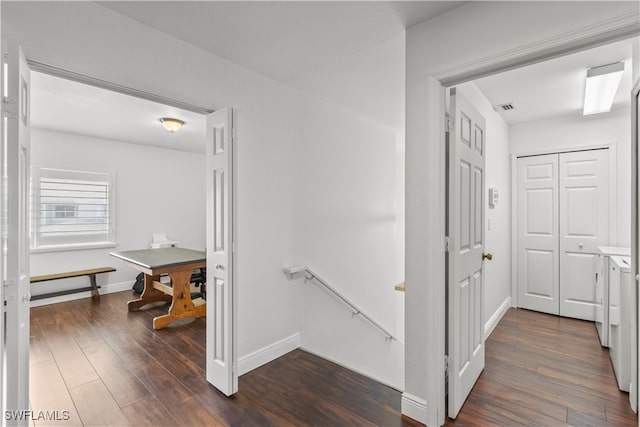 hall with baseboards, dark wood finished floors, and an upstairs landing