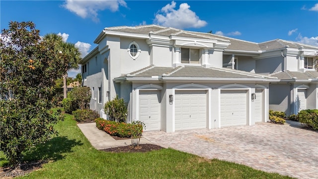 view of front of home featuring a garage, decorative driveway, a tile roof, and stucco siding